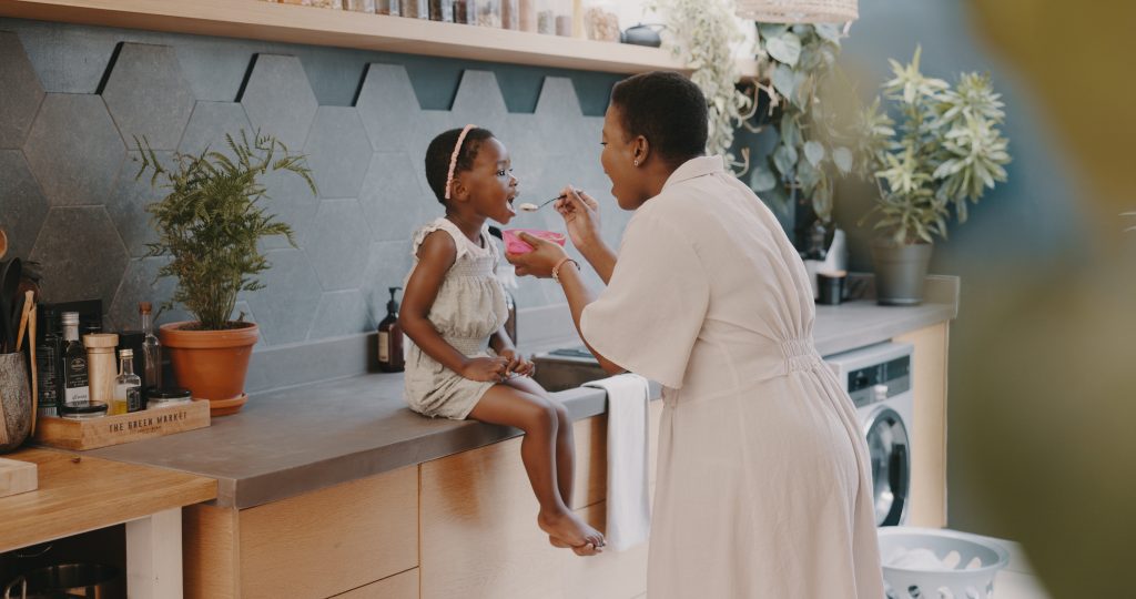 Family, children and love with a girl and mother playing together in the kitchen of their home. Kid.